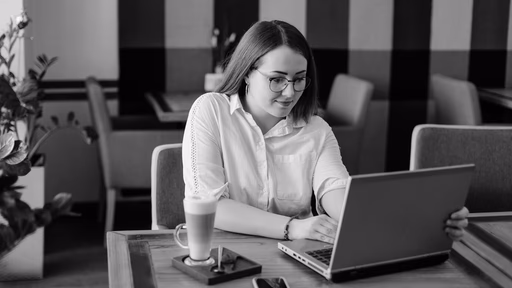 A woman working on a laptop at a cafe table.